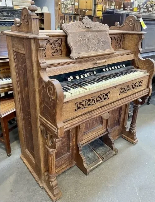 Salvaged antique pump organ with ornate carved wood, keyboard, and foot pedals. This unique piece of vintage furniture was available secondhand from our Baltimore non-profit.