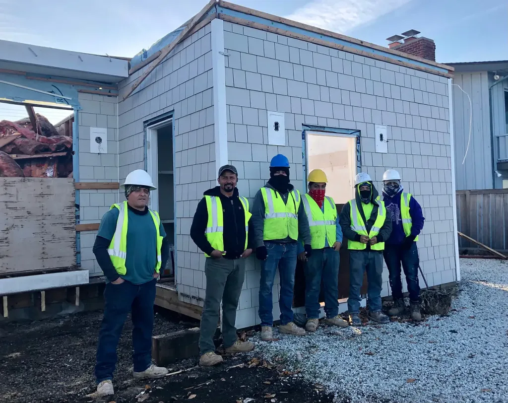 Construction crew in safety gear on a job site, illustrating the use of secondhand and salvaged building materials for sustainable home improvement. Find quality used building materials at our Baltimore non-profit.