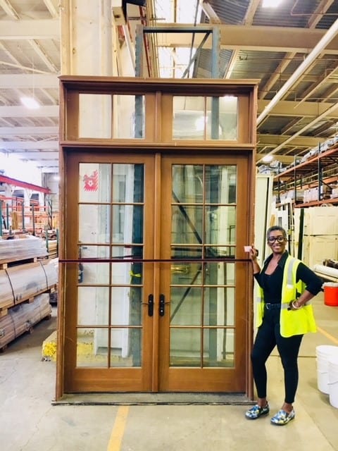 Large salvaged wood French doors with transom, featuring glass panes and dark hardware. Find unique secondhand building materials for home improvement from our Baltimore non-profit.