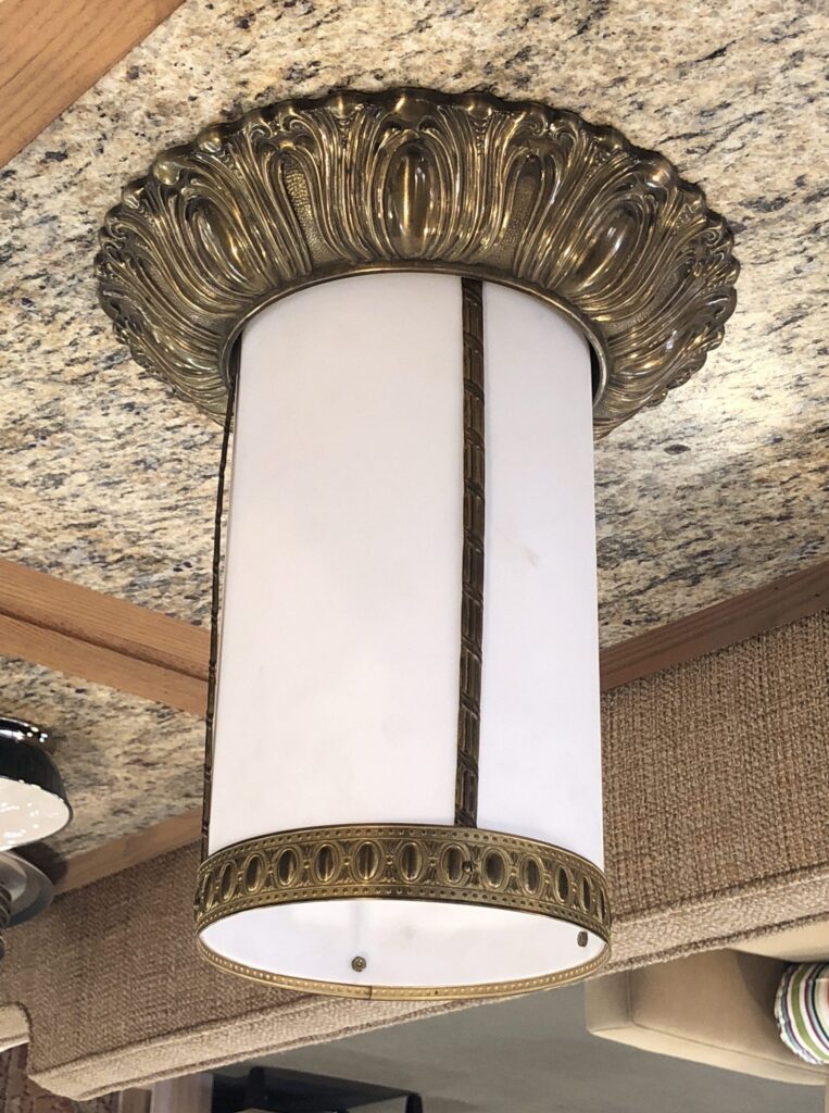 Ornate salvaged vintage brass ceiling light fixture with a white cylindrical shade and decorative antique hardware. Find unique secondhand lighting for your home.