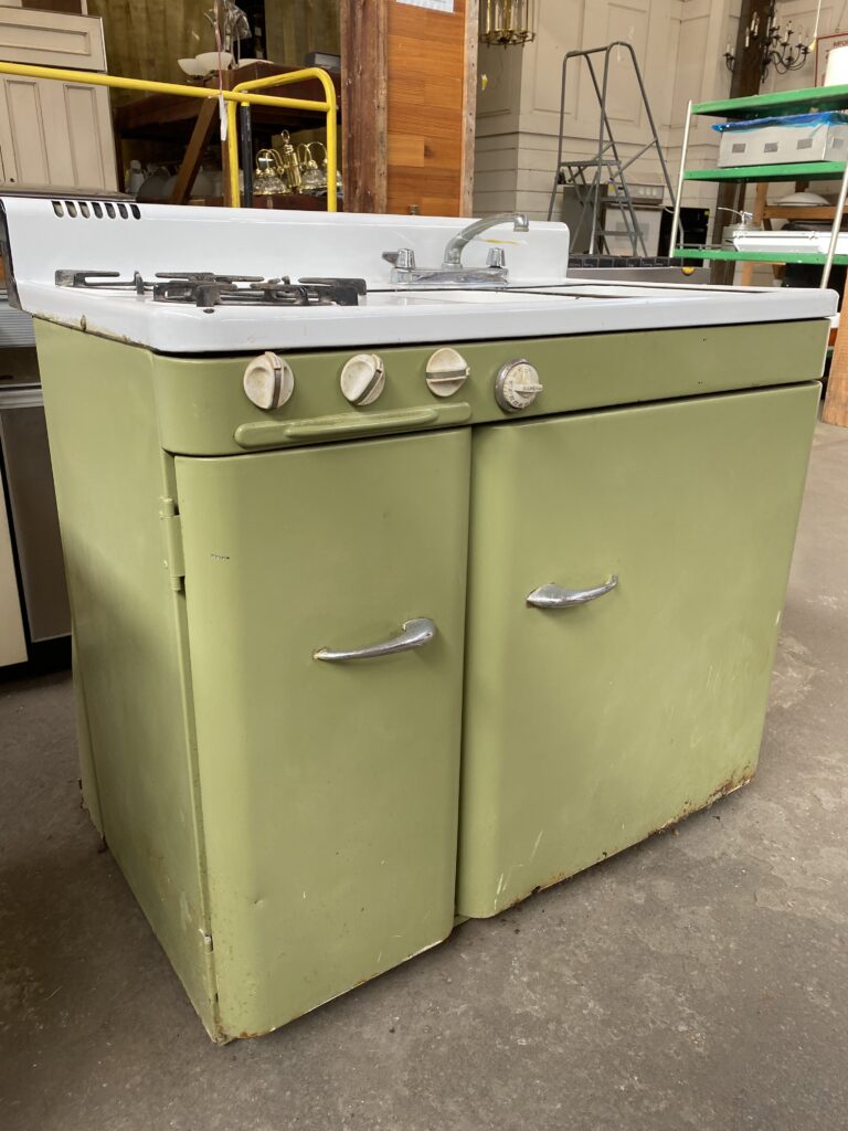 Vintage avocado green compact kitchen unit with gas stove, sink, and cabinets. This salvaged, secondhand piece of vintage furniture is available at Second Chance, Inc., a Baltimore non-profit offering unique used building materials and home decor.